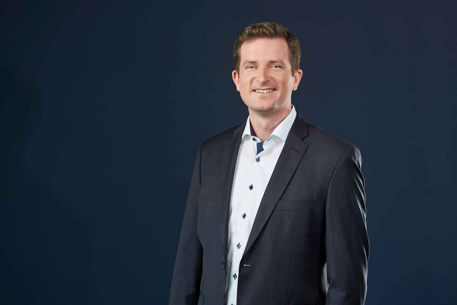 Home 21 Business-Portrait eines Mannes im dunklen Anzug.