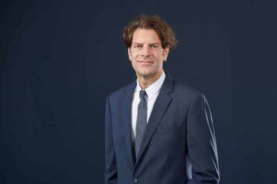 Home 7 Business-Portrait eines Mannes im dunklen Anzug.